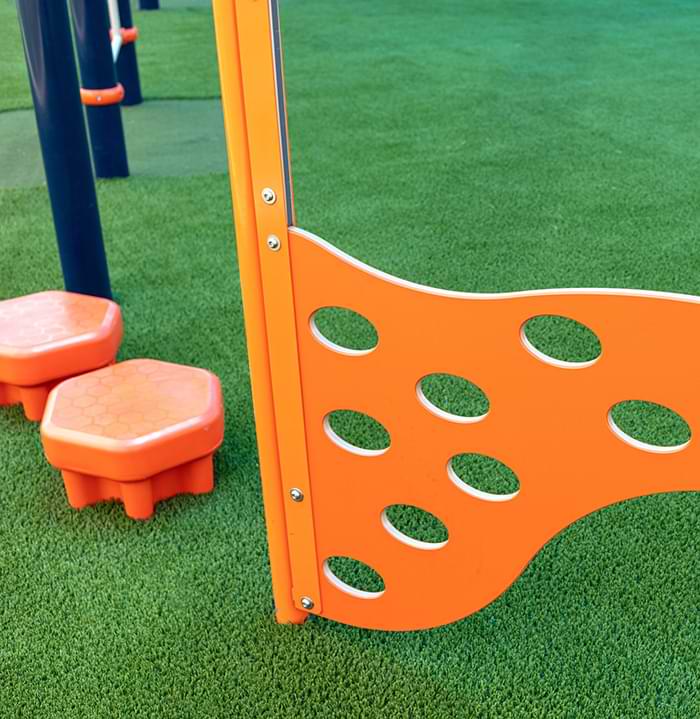 Orange playground equipment installed on artificial grass